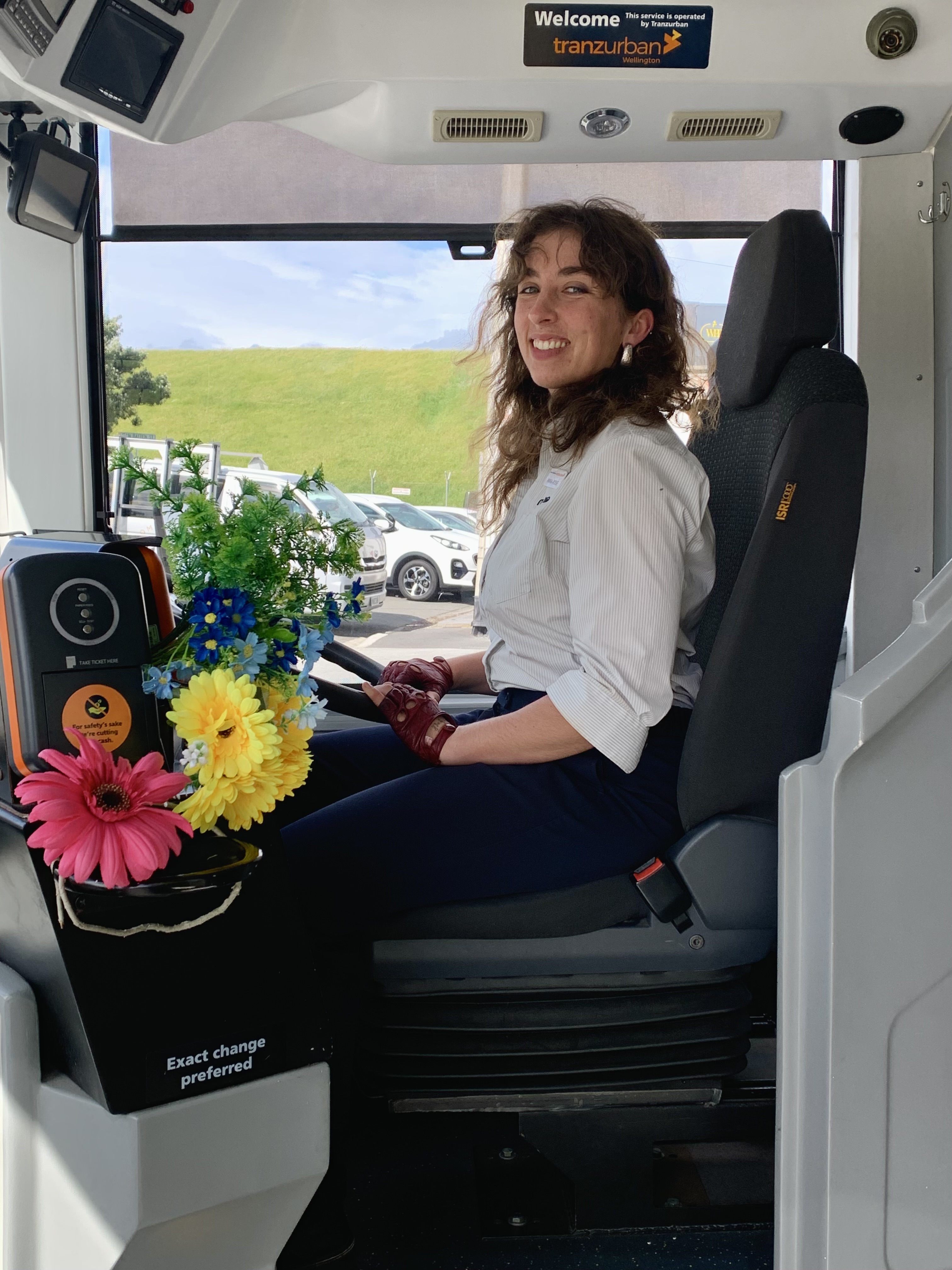 Anna-Rose in the driver's seat of the bus with her bouquet of flowers